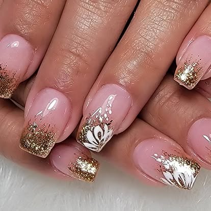 Soft nude manicure with gold glitter French tips and white floral art